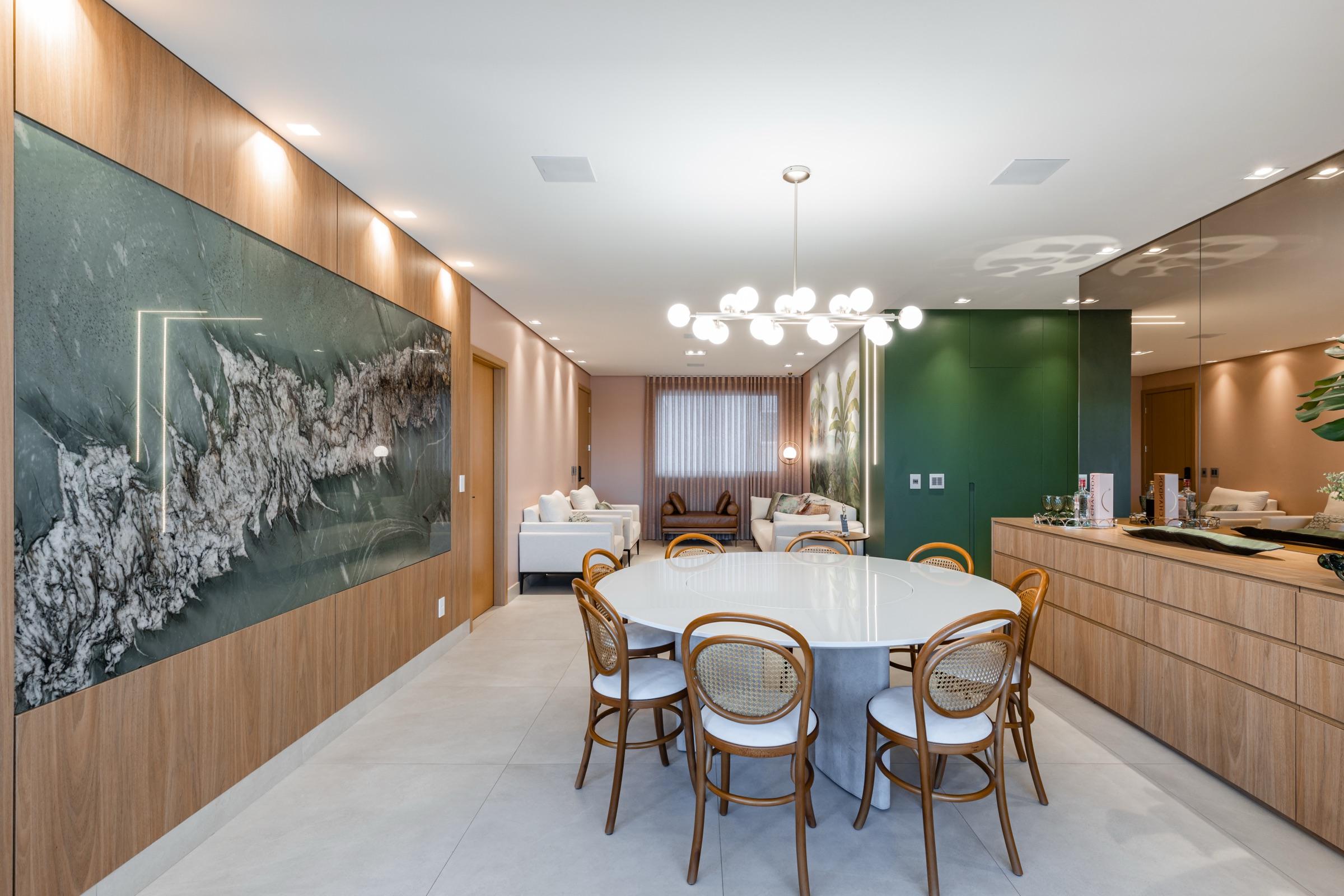 Sala de jantar com painel em madeira, arte emoldurada e adega integrada.
