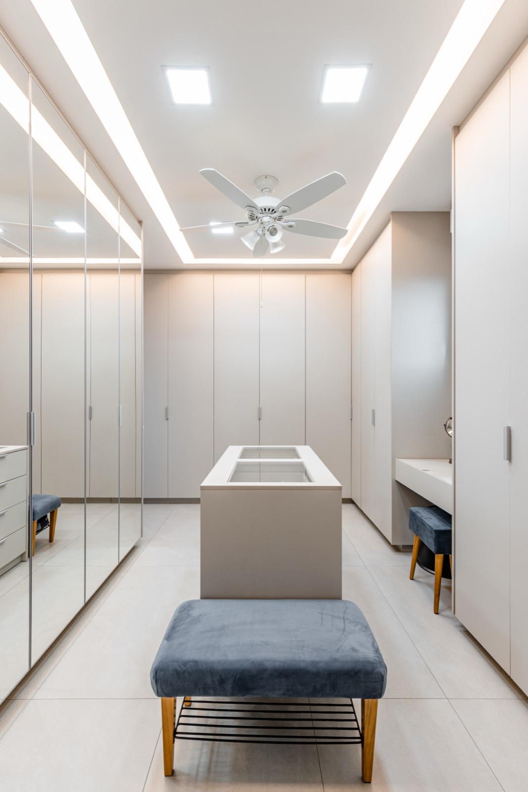 Closet amplo com ilha central e portas espelhadas.